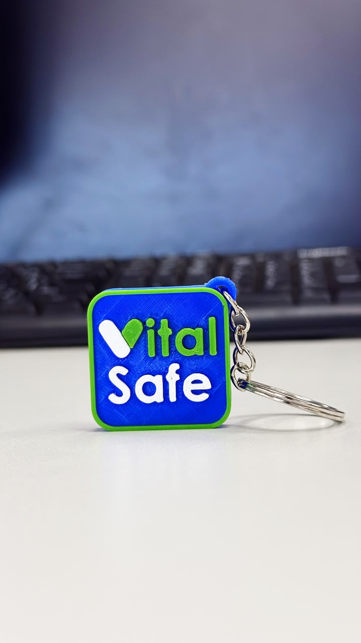 Chaveiro NFC azul com borda verde e a marca VitalSafe, preso a uma argola